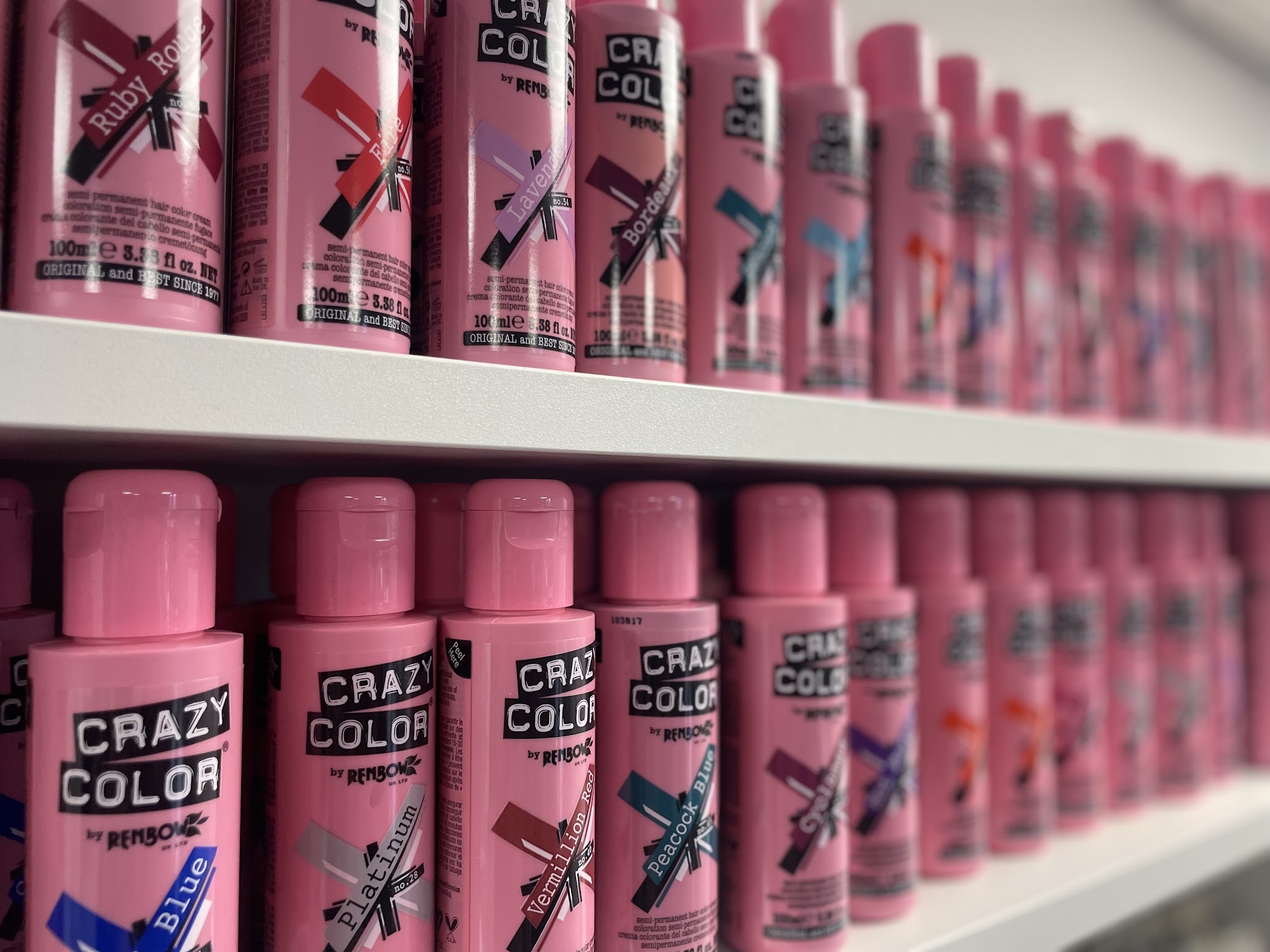 Een lange rij roze flessen Crazy Color haarverf op een plank